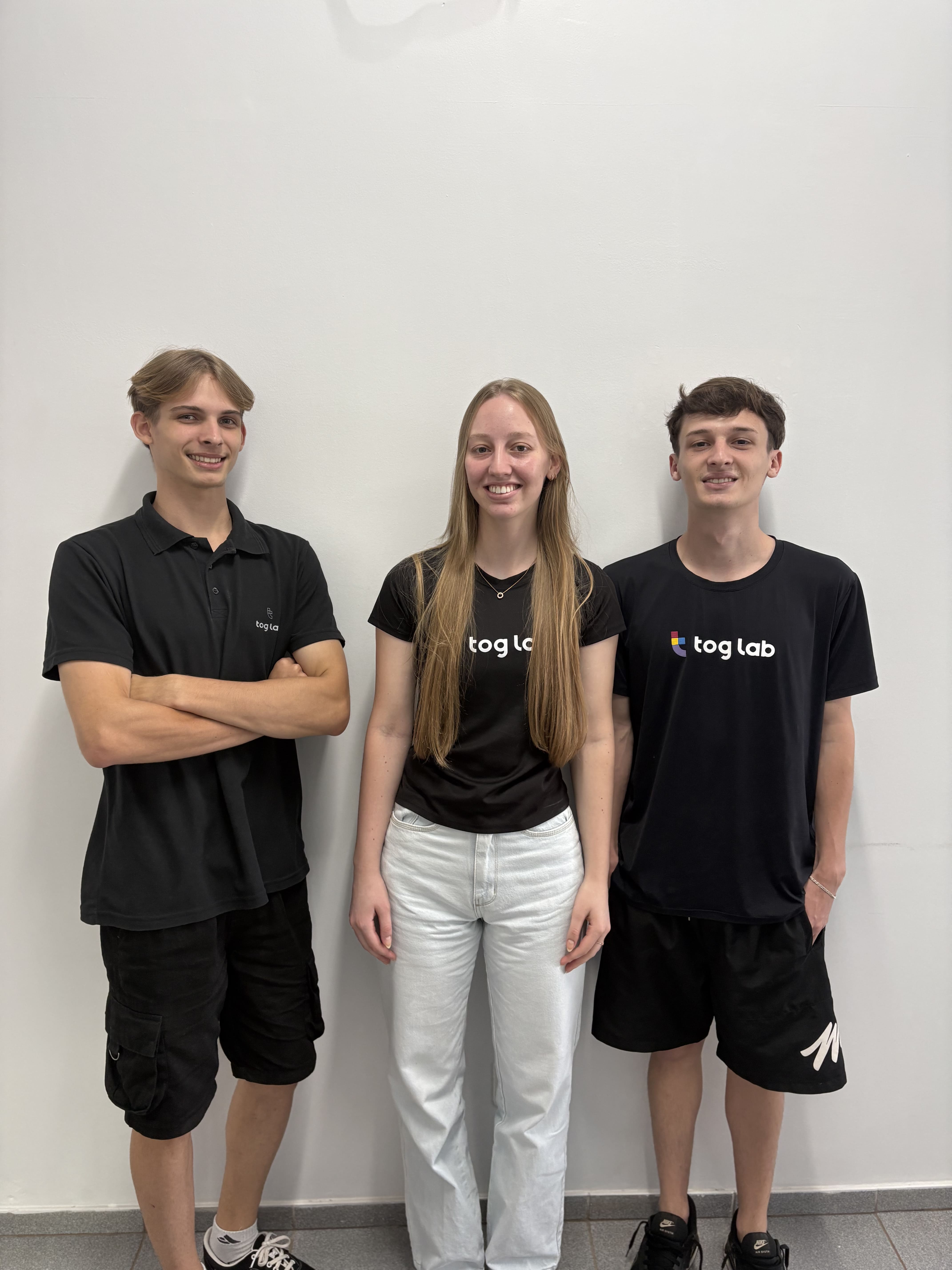 Tog Lab team group portrait. Three Tog Lab team members standing side by side wearing black company shirts against a light wall.